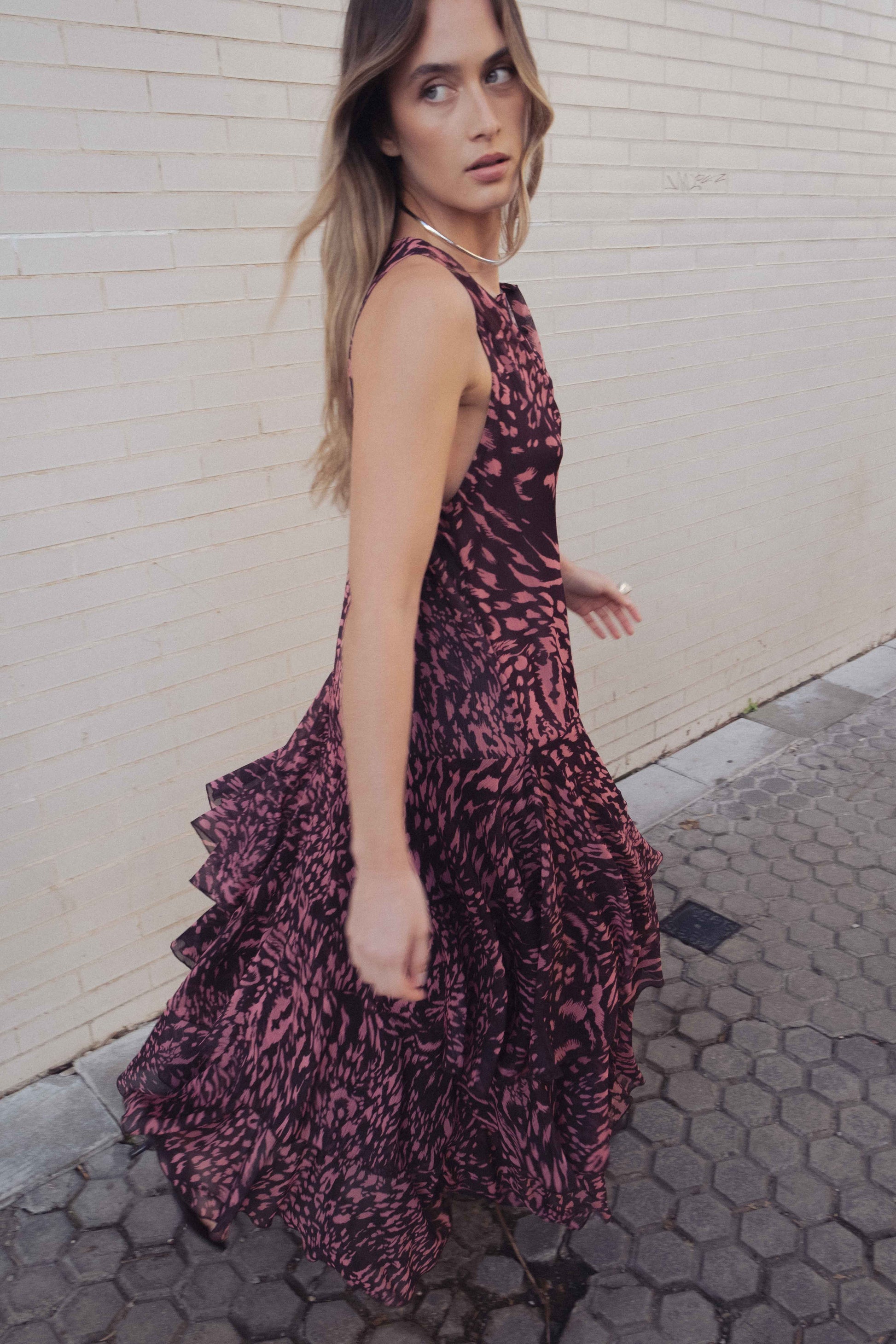 Mujer posando con Vestido Sunset de HiCute, vestido largo fluido color granate y rosa con estampado animal y volantes.